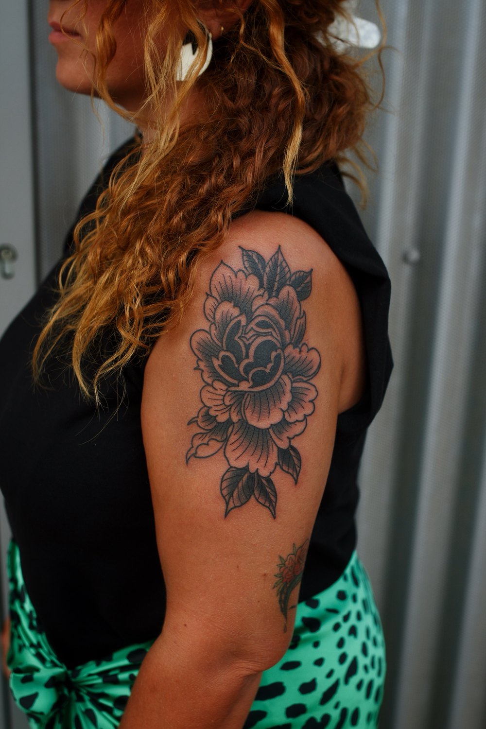 Tatuaje tradicional de peonía en negro y gris con líneas clásicas y buen contraste
